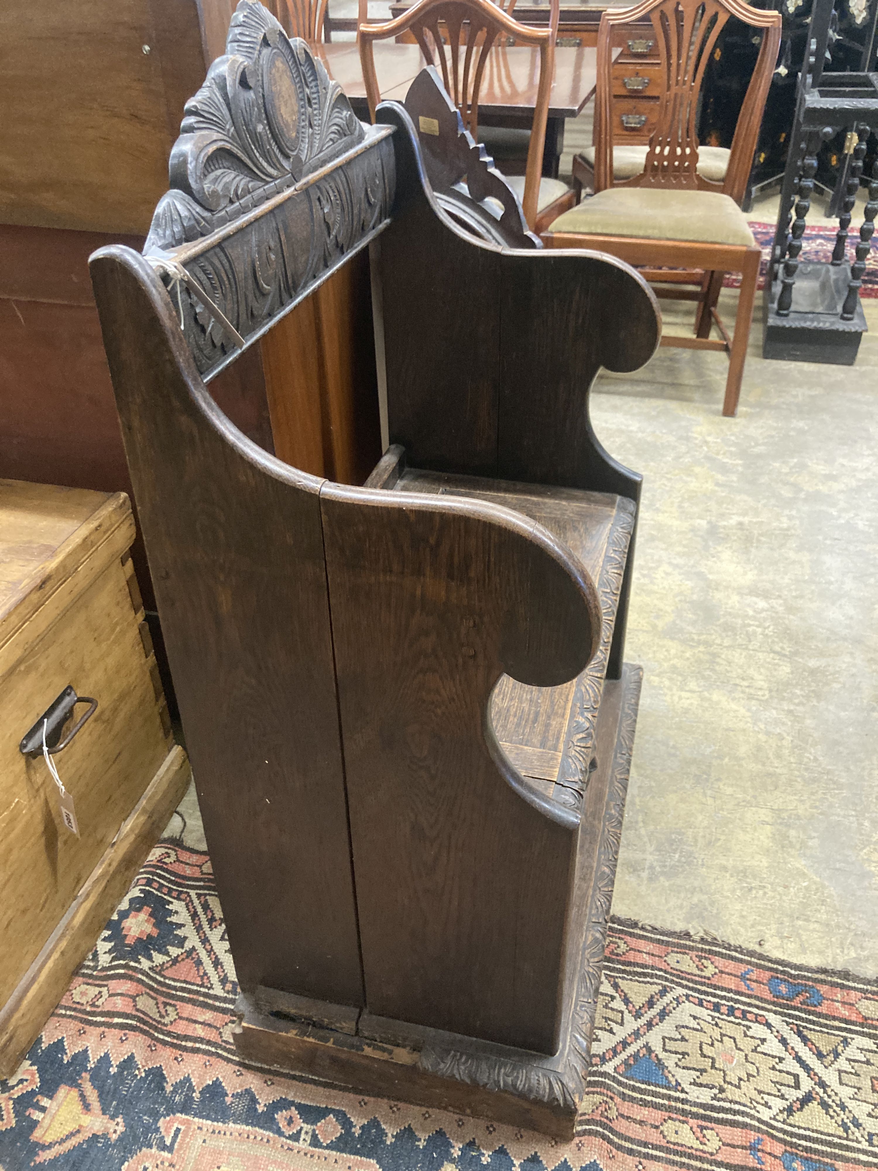 A small Flemish carved oak box seat settle, width 65cm, depth 40cm, height 104cm